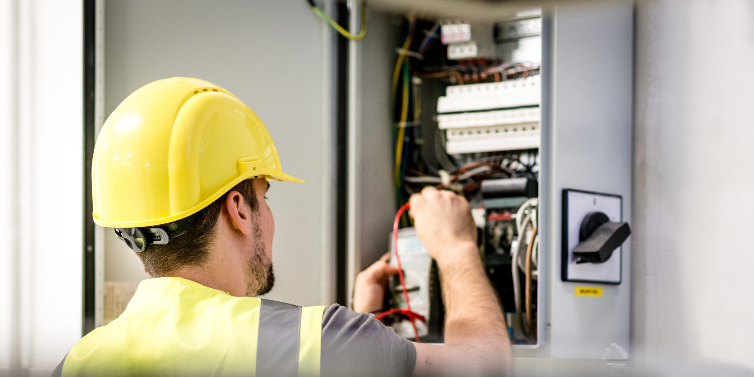 Electrician repairing circuit breakers in electric panel, Modern Circuit Interrupters.