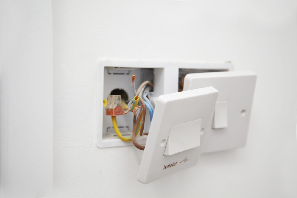 Close-up of wiring a 13 amp electrical socket with exposed wires, ensuring Electrical Code Compliance.
