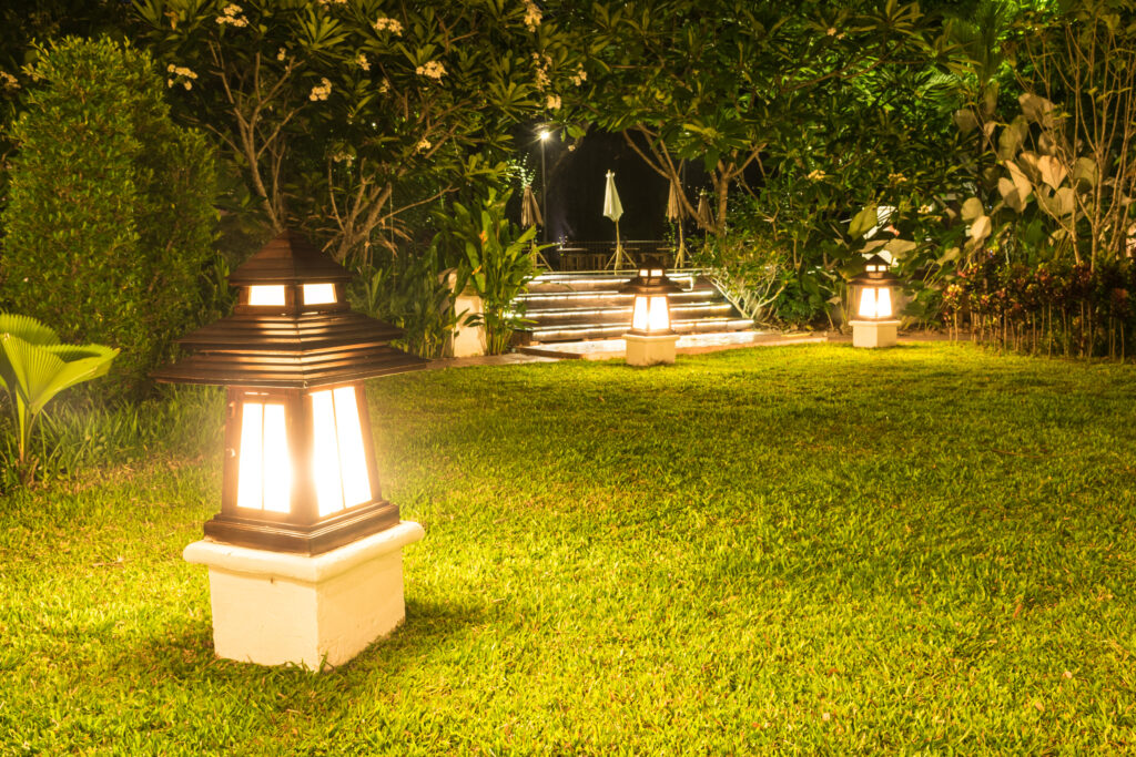 A lighting lamp casting a warm orange glow in the garden at night.