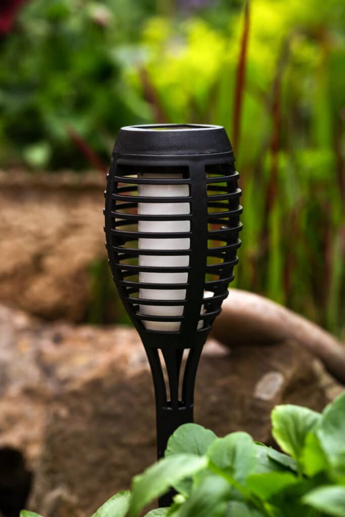 Small solar garden light in a flower bed with stones, an energy-saving and environmentally friendly outdoor lighting.