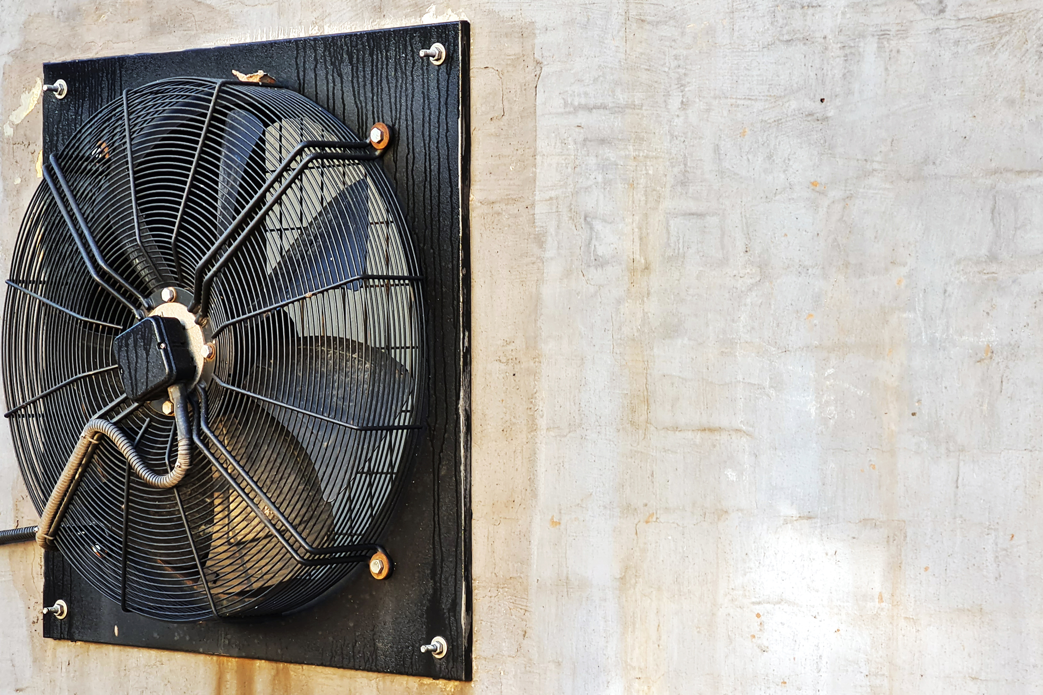 Big industrial fans in a white brick wall of a factory.