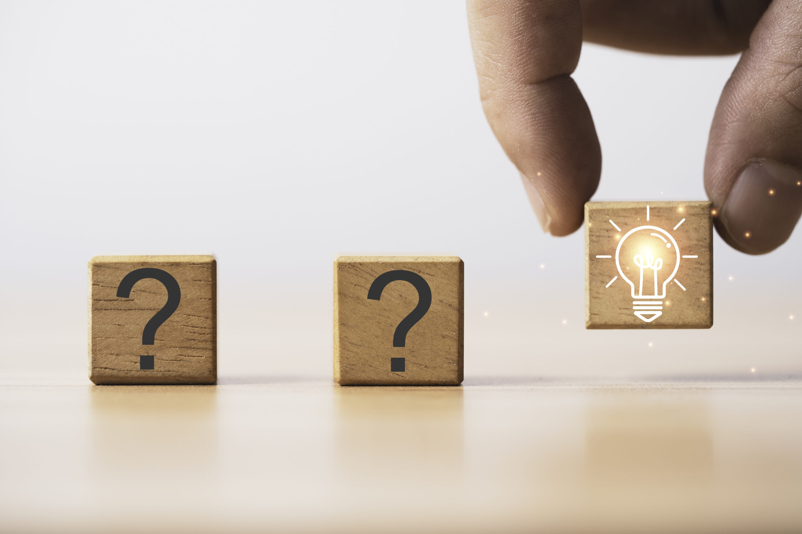 Hand holding glowing light bulb among question mark, Custom Lighting Solutions.
